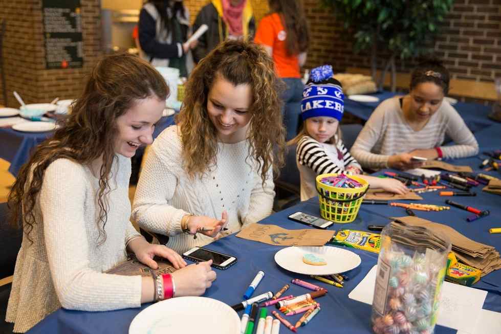 Students doing crafts with young kids at family weekend